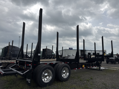 Log trailer with multiple vertical stakes and dual tandem axles parked at lot. VIN 1V9PD422XTN062084 visible on listing; Viking tag on trailer.