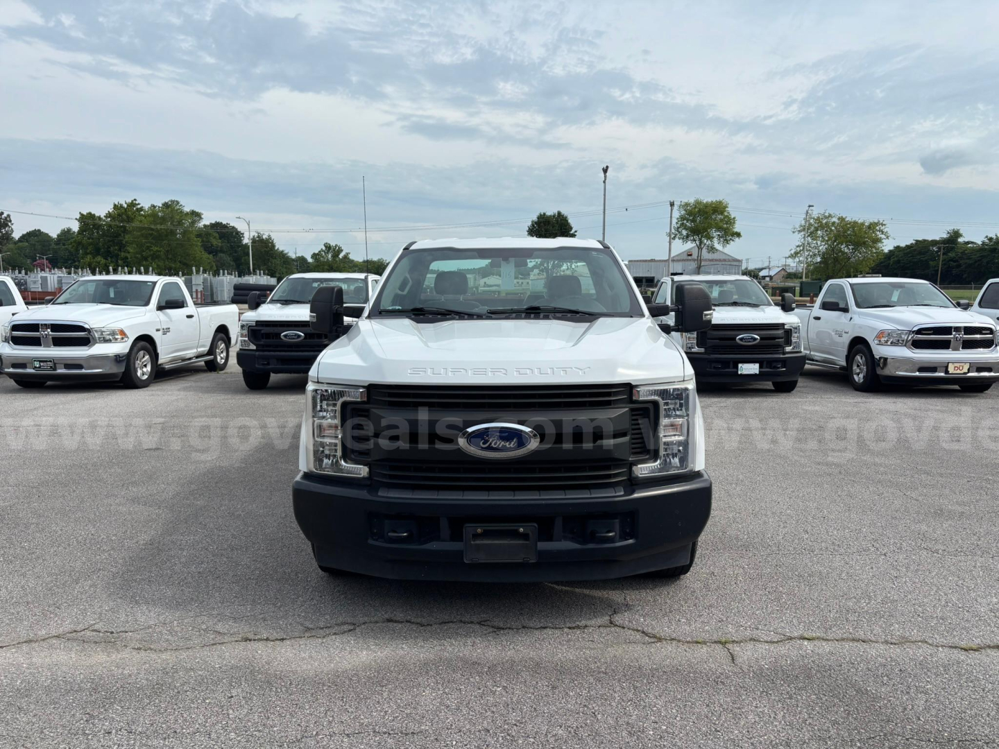 Ford F-250 front view showing chrome grille, headlights, and bumper in a parking lot.
