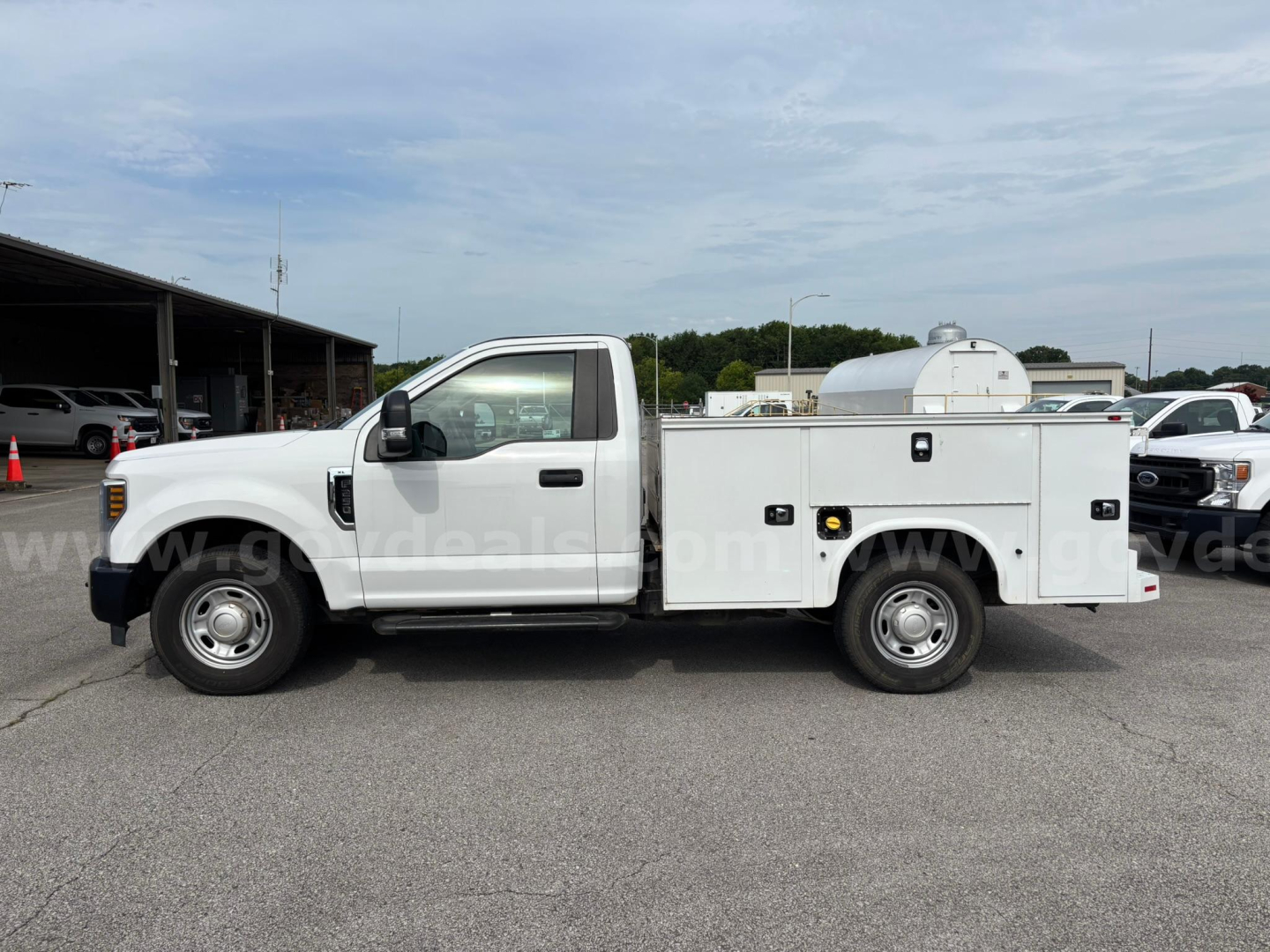 Ford F-250 utility/service bed truck in side view with storage box and equipment cabinet, white exterior, regular cab, standard wheels.