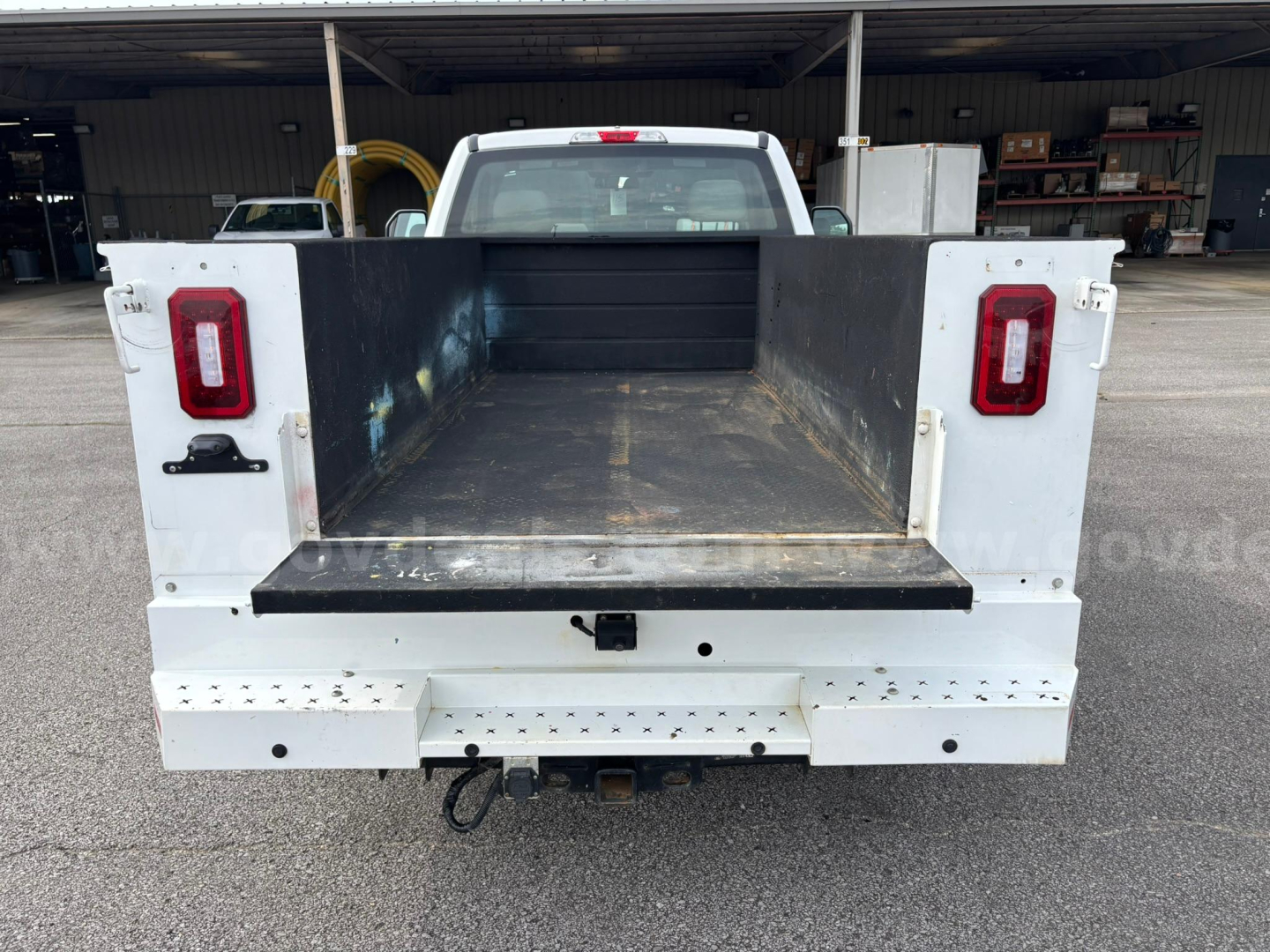 Truck bed of a 2019 Ford F-250 with open cargo area, white tailgate sides, red taillights, and hitch receiver visible.