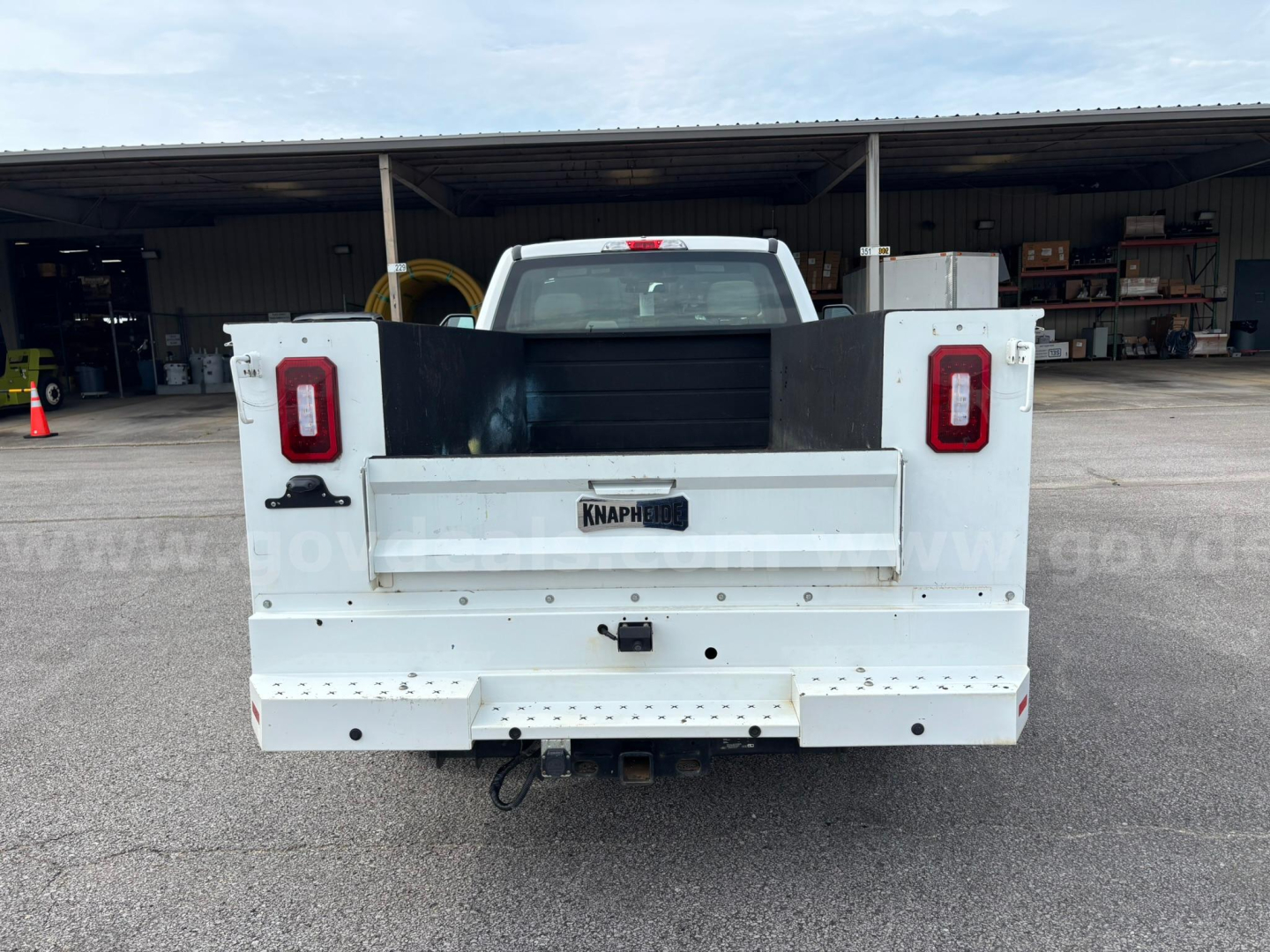 Back view of a white Ford pickup truck flatbed/utility body with taillights and rear bumper, showing Knapherr brand plate area and hitch.