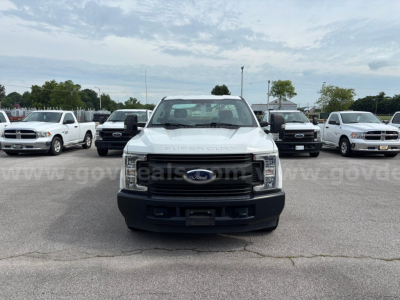 Ford F-250 front view showing chrome grille, headlights, and bumper in a parking lot.