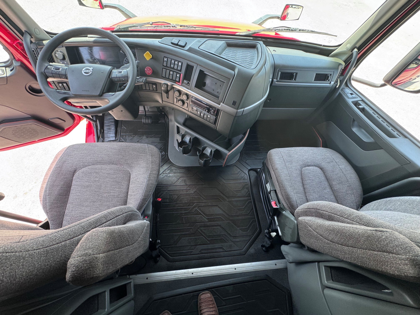 Interior cabin view of a 2021 Volvo VNL64T760 showing steering wheel, dashboard with controls, and two front seats from a slightly raised angle.
