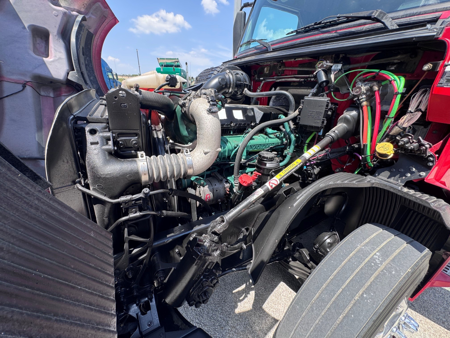 View of a Volvo VNL64T760 engine bay with intake, hoses, and wiring visible; Turbocharger, coolant reservoir, and various fluid lines present.