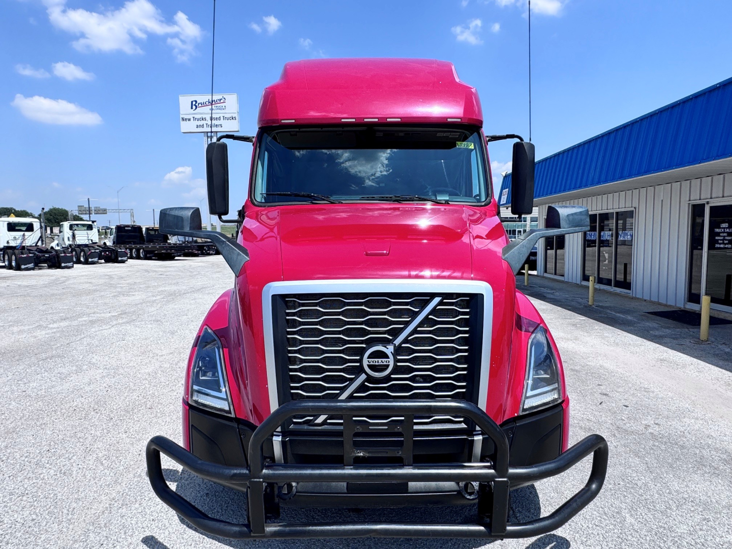 Volvo VNL64T760 truck front view with large chrome grille, black bull guard, pink cab, and side mirrors.