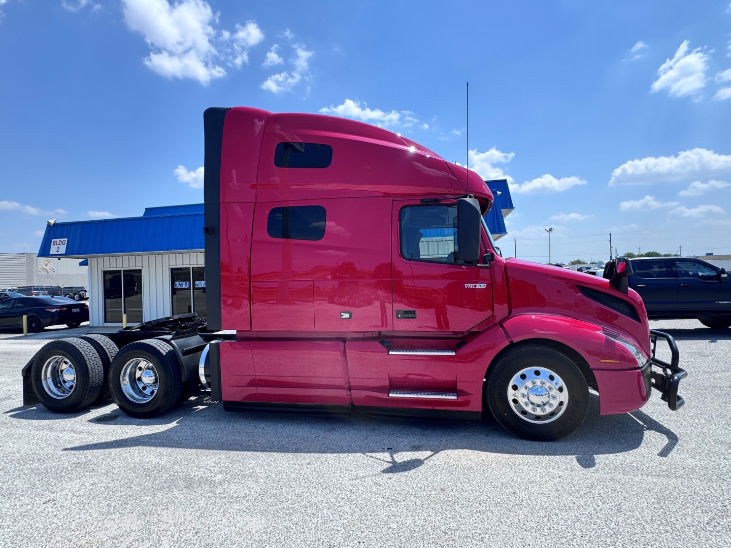 Volvo VNL64T760 sleeper cab tractor in side view showing pink exterior, bunk area, chrome wheels, dual rear axles, and tandem axle configuration.