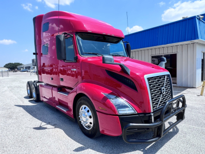 Volvo VNL64T760 sleeper cab tractor showing bright pink exterior and front bull bar with grille guard.