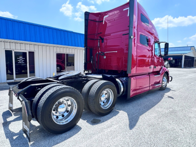 Truck cab and rear wheels of a red 2021 Volvo VNL64T760 tractor in a dealership lot, showing sleeper cab, DPF area, and dual rear axles.