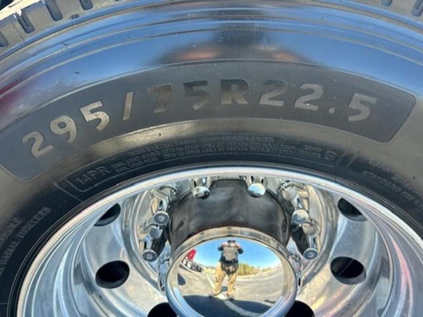 Tire showing size 295/75R22.5 and polished wheel with reflective hubcap.