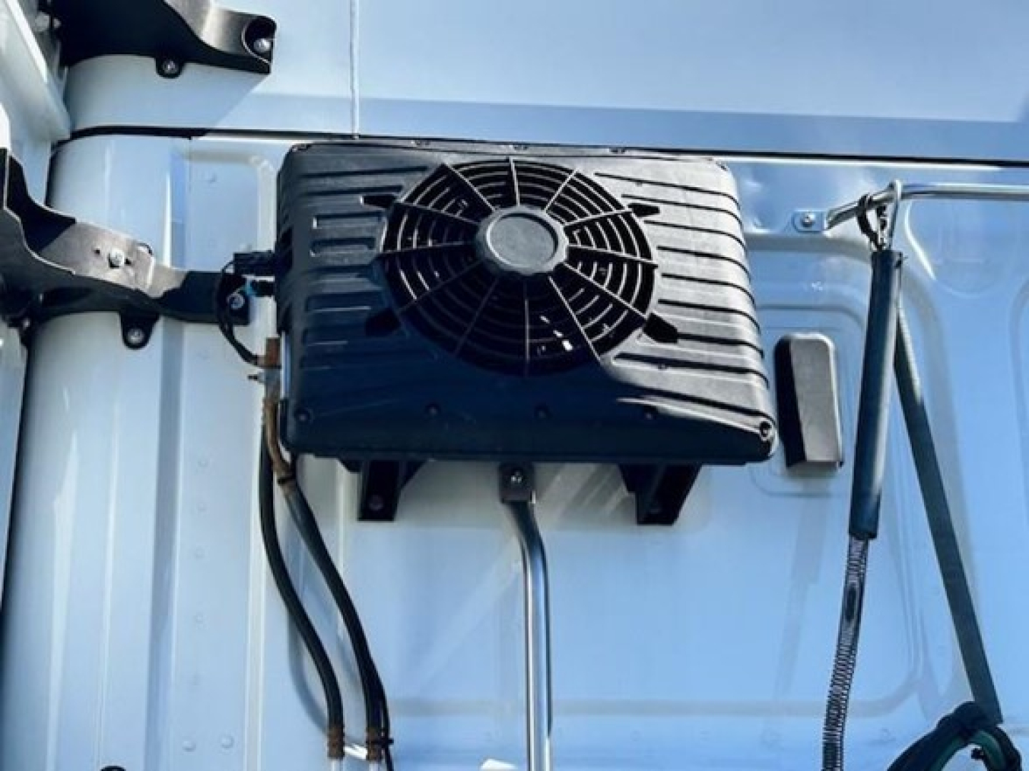 Tractor cab exterior showing a roof-mounted or side-mounted cooling unit with fan grille and tubing on a Freightliner Cascadia 126. visible text not present.