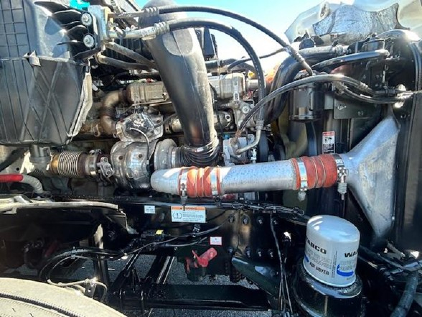 Diesel engine bay of a 2022 Freightliner Cascadia 126 showing hoses, turbo, filter canister, and coolant lines.