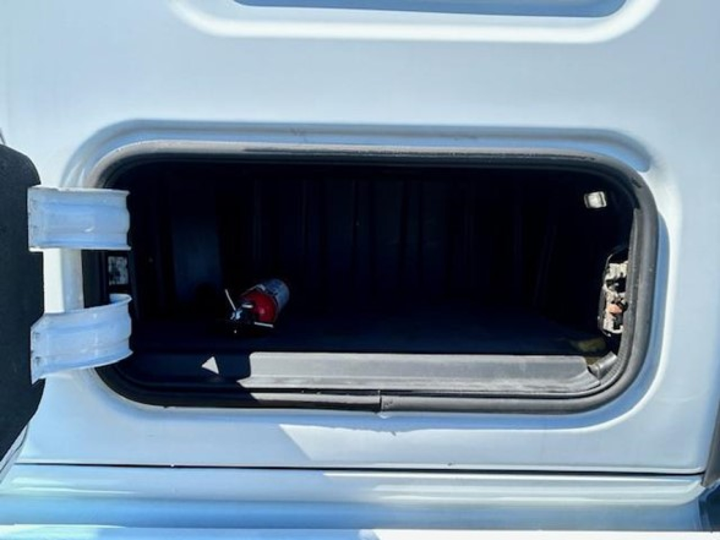 Truck cab storage hatch open showing interior storage area with hinge and latch