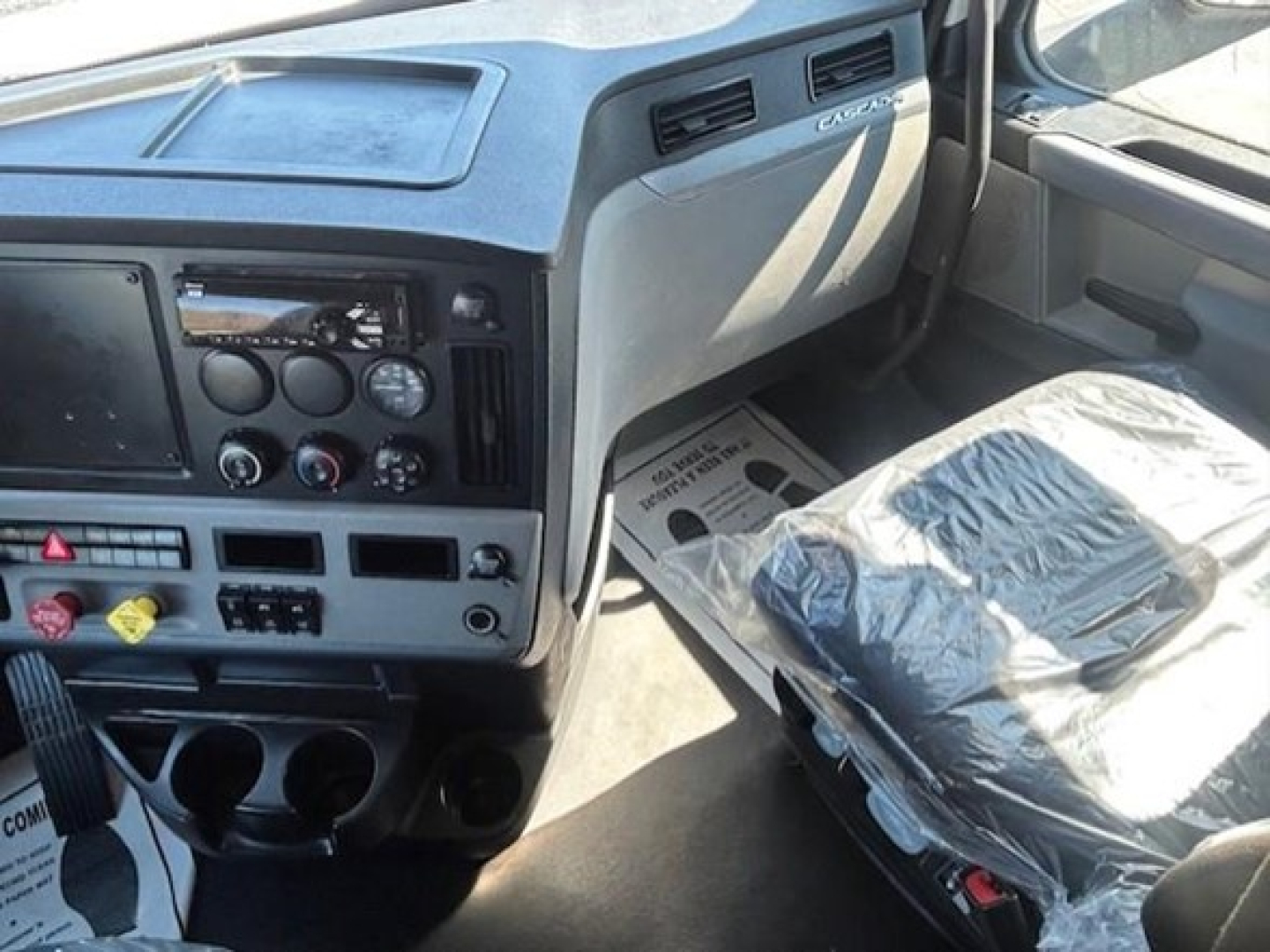Freightliner Cascadia truck cabin dashboard and passenger seat visible.
