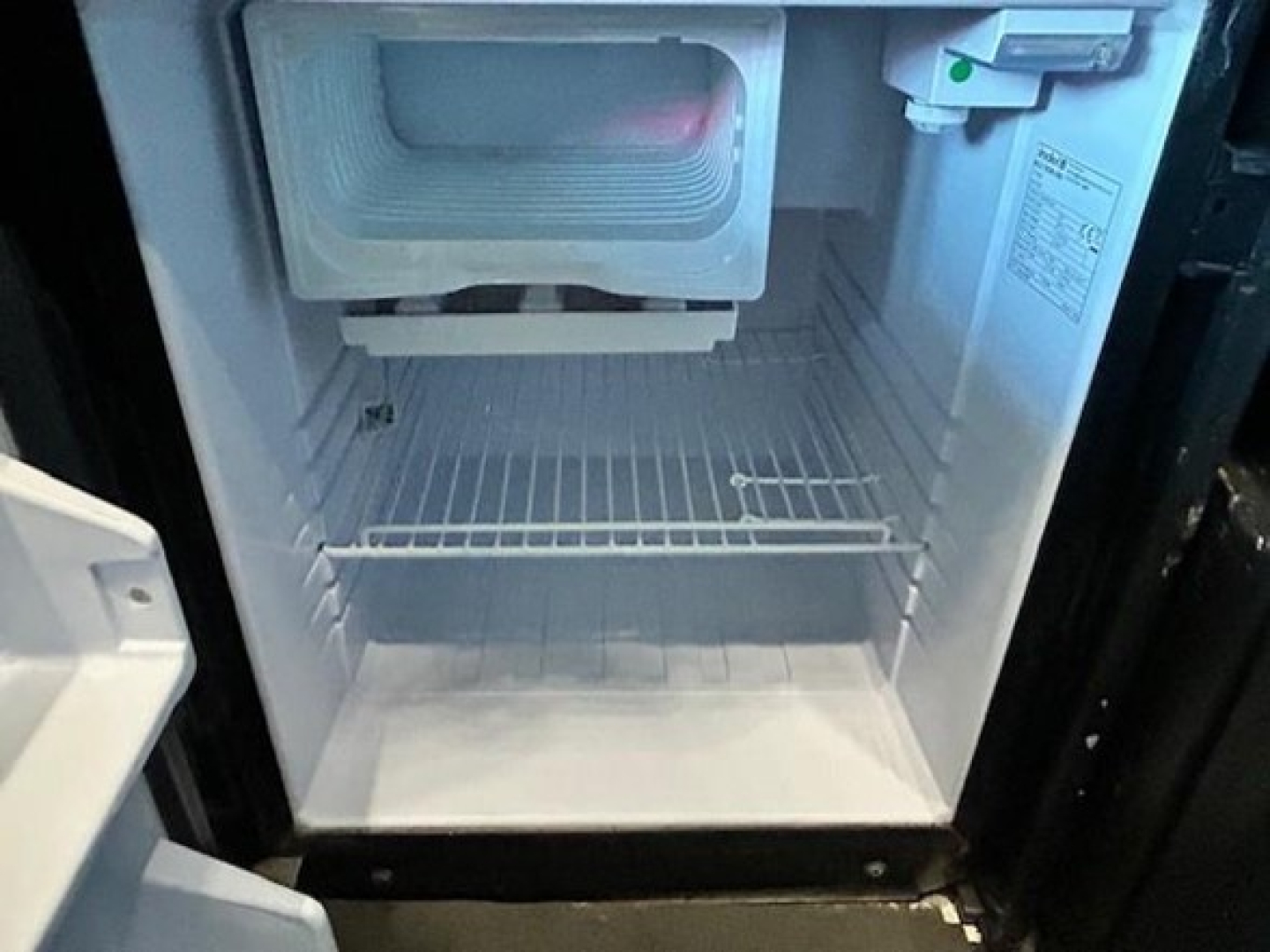 Freightliner Cascadia image showing an open small freezer/refrigerator compartment inside the cab or sleeper area with empty shelves.