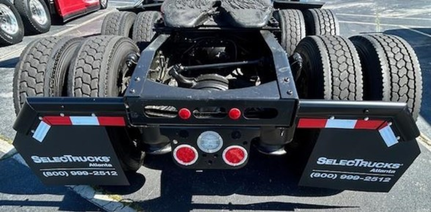 Freightliner Cascadia chassis rear view showing dual rear axles and wheel setup with taillight panels and bumper stickers.