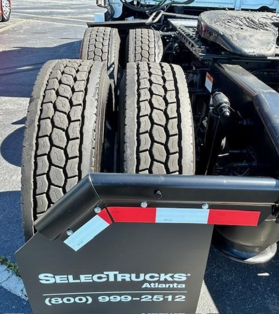 Rear view of a Freightliner Cascadia tractor with dual rear axles and mudflap showing 'SelectTrucks Atlanta' branding and contact number.