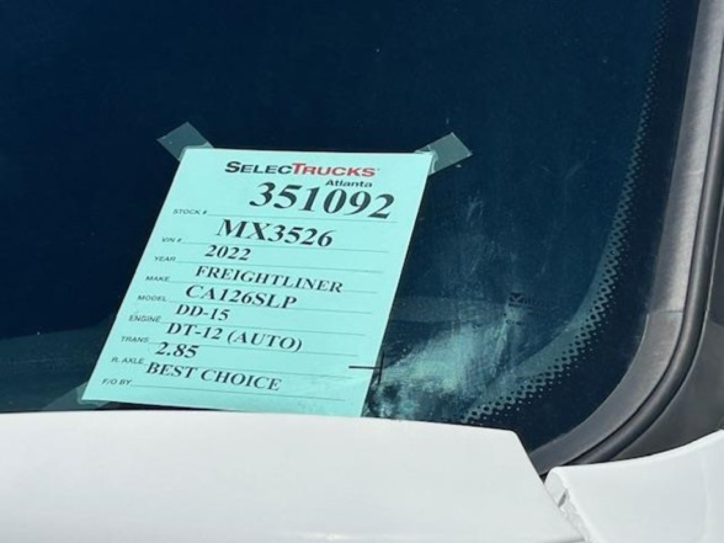 Tag on windshield showing stock number 351092, VIN MX3526, year 2022, make Freightliner, model DD-15, engine DT-12 (AUTO), weight 2.85, best choice.