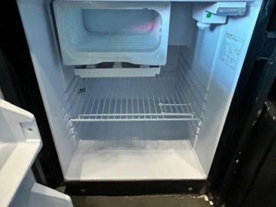 Freightliner Cascadia image showing an open small freezer/refrigerator compartment inside the cab or sleeper area with empty shelves.