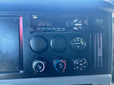 Dashboard of a Freightliner Cascadia interior showing climate controls, engine gauges, and a radio display panel.