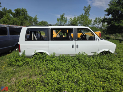 White 2001 Chevrolet Astro van side view in grassy lot with open windows and visible interior seats.