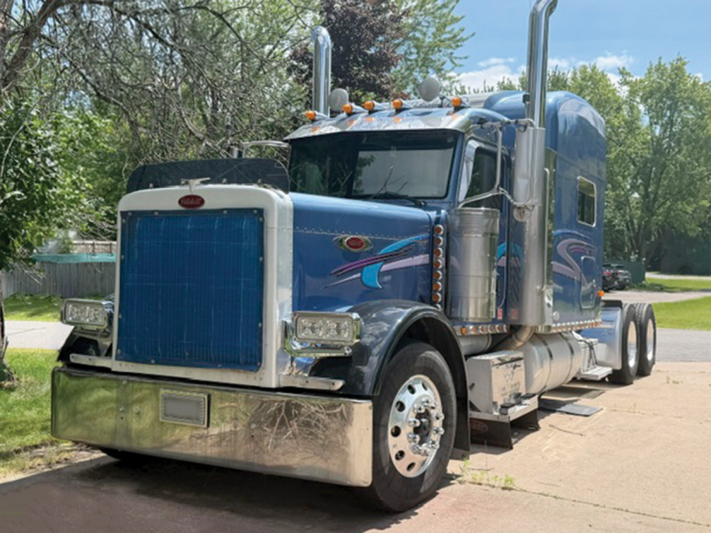 Peterbilt 379 UltraCab extended hood semi-truck with chrome bumper and blue-gray paint, front grille, sleeper cab, dual exhaust stacks.