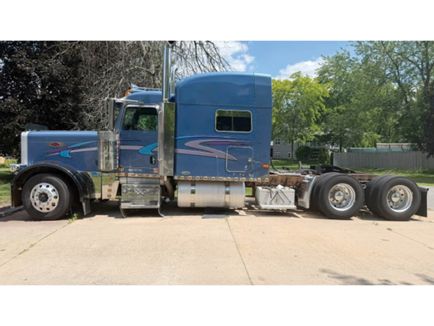 Peterbilt 379 UltraCab extended hood tractor side view showing blue custom paint with chrome fuel tanks and dual rear axles.
