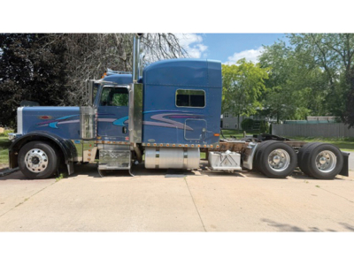Peterbilt 379 UltraCab extended hood tractor side view showing blue custom paint with chrome fuel tanks and dual rear axles.