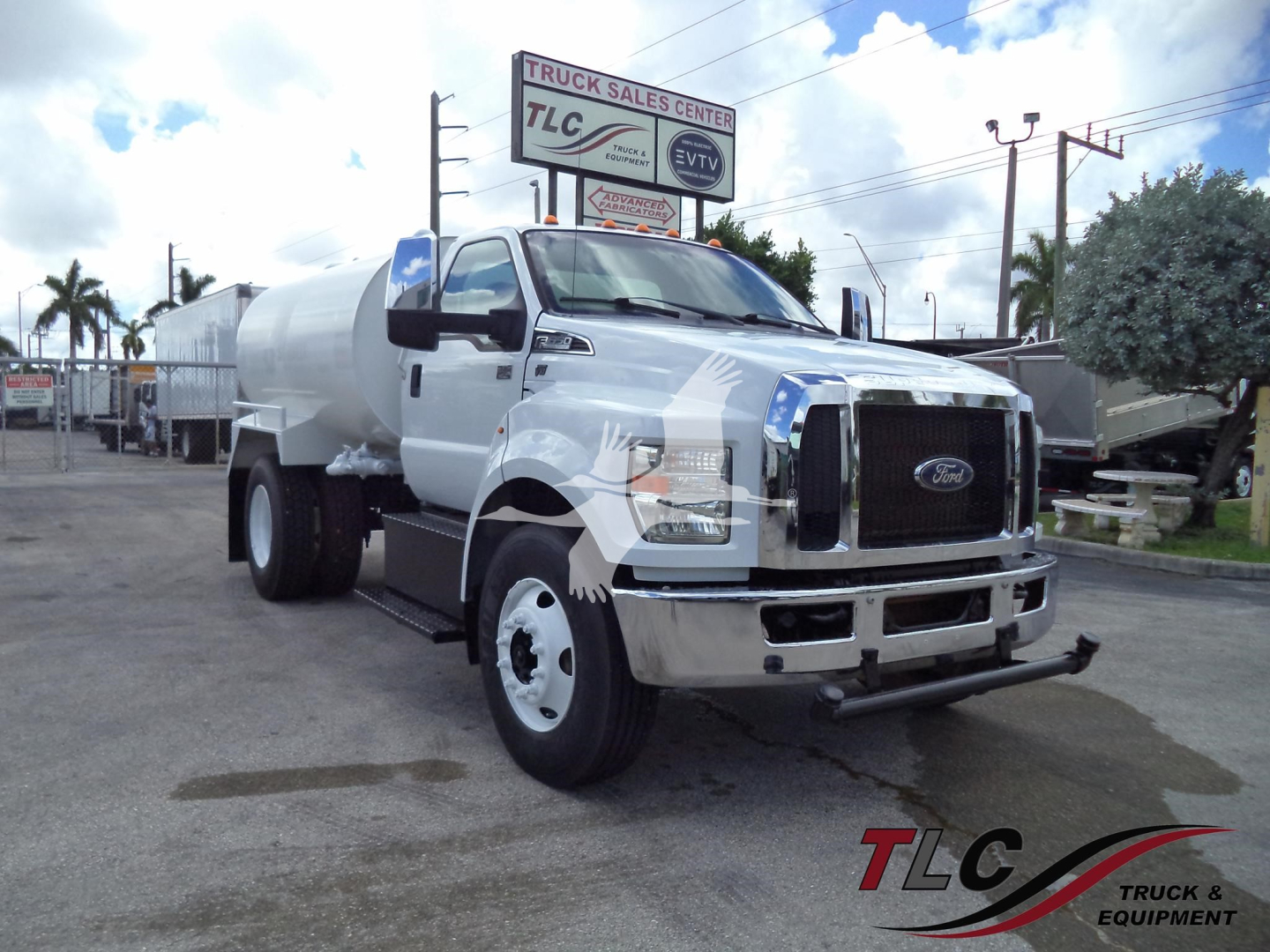 Front-left view of a white 2017 Ford F-650 truck with a large cylindrical tank mounted on back, showing bumper, grille, and TLC signage in background.