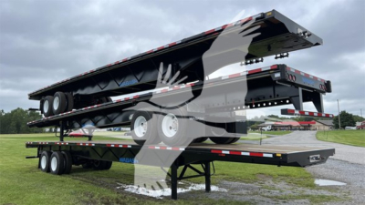 Wabash steel spring slider flatbed trailer in raised position showing dual rear axles and loading deck with reflective tape