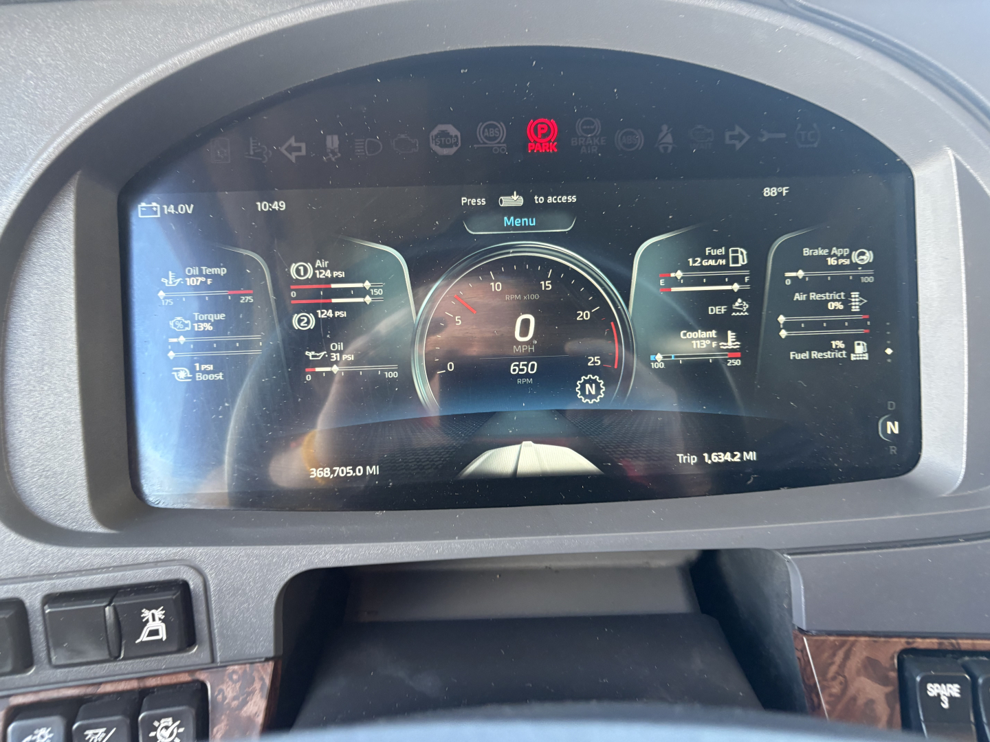 Kenworth dashboard display with multiple digital gauges showing speedometer, trip miles, engine data, and various warning icons.