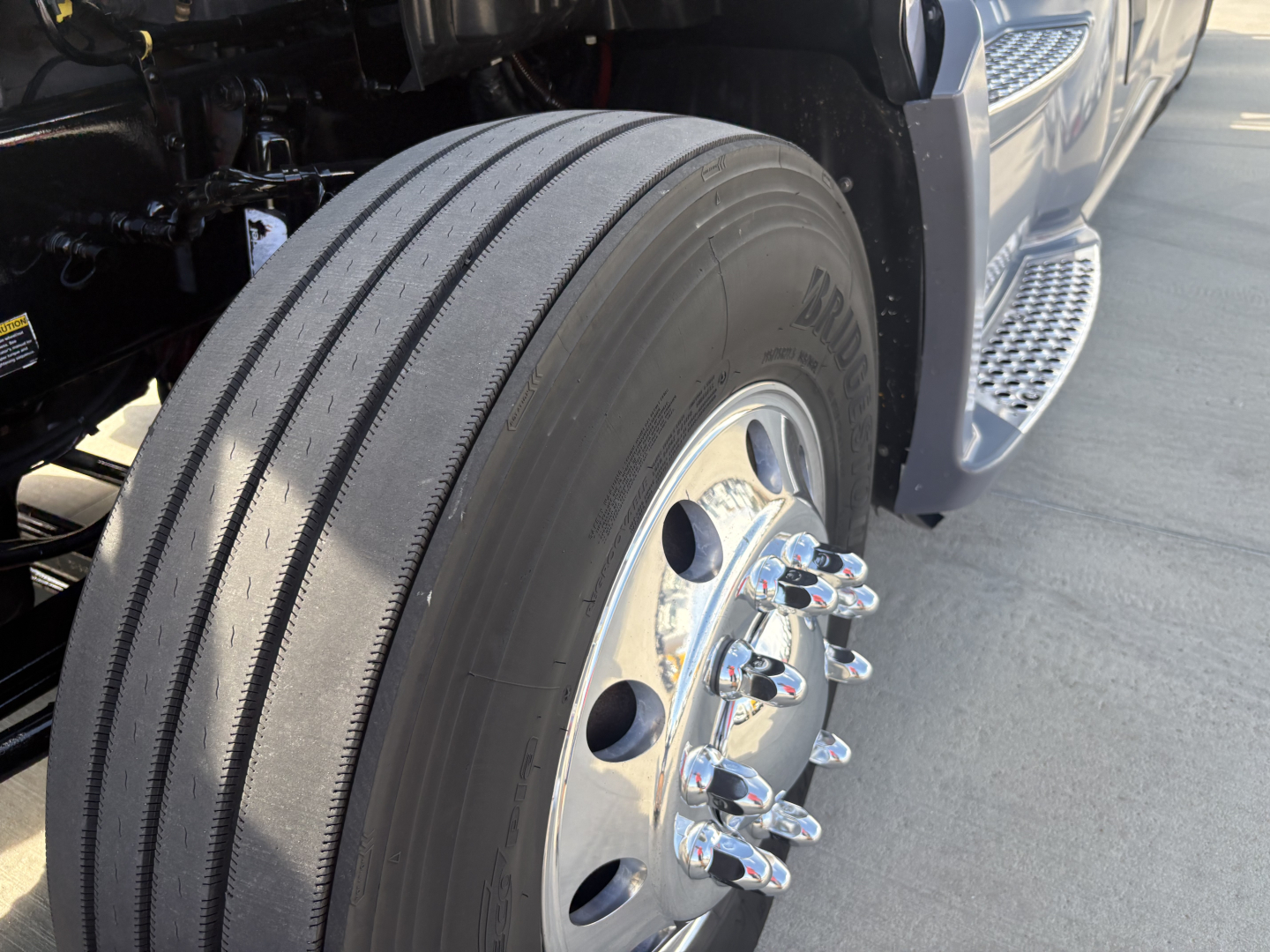 Kenworth T680 front wheel and tire with chrome lug nuts and dual tread pattern visible, part of the right-front wheel area.