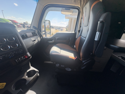 Kenworth T680 cab interior view from the driver's seat showing dashboard controls, center console, and driver seat with two-tone upholstery.
