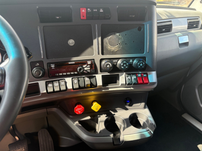 Kenworth T680 dash view showing center console with climate controls, switches, and cup holders.