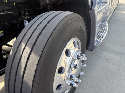 Kenworth T680 front wheel and tire with chrome lug nuts and dual tread pattern visible, part of the right-front wheel area.