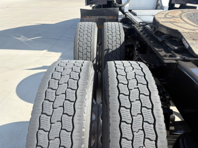 Kenworth truck rear wheel area showing dual rear axles with treaded tires and fifth wheel platform, generic exterior details visible.