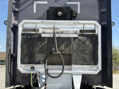 Kenworth T680 rear view showing radiator, license/step area and various hoses; black exterior with metal frame around rear opening.