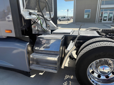 Kenworth T680 side step area showing chrome steps, fuel/air lines, and cab access area near front wheel.