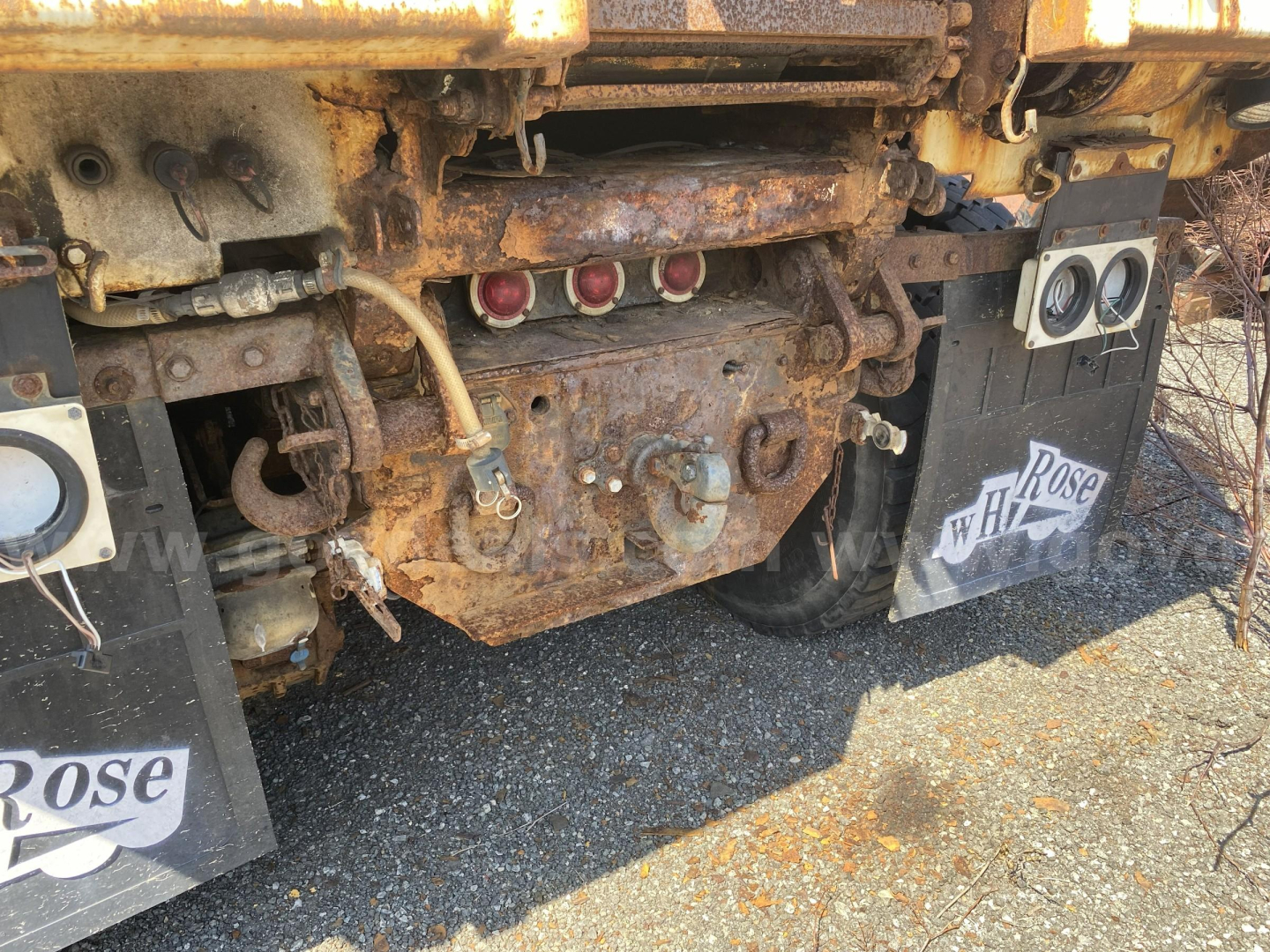 Truck rear showing rusty chassis with hydraulic lines, exhaust manifold, and tow hitch area on Mack CTP713.