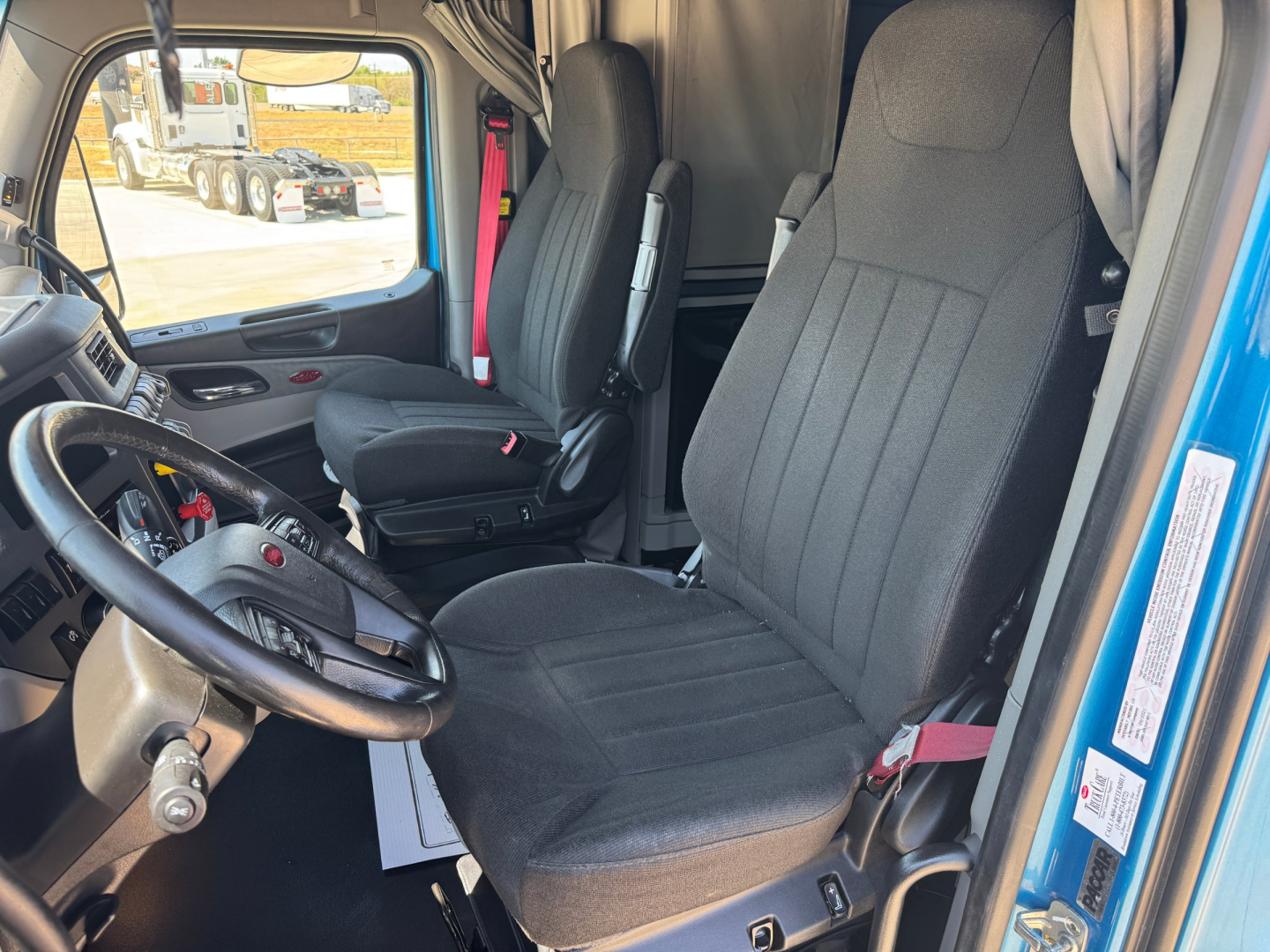 Truck cab interior of a 2022 Peterbilt 579 sleeper with driver and passenger seats and steering wheel.