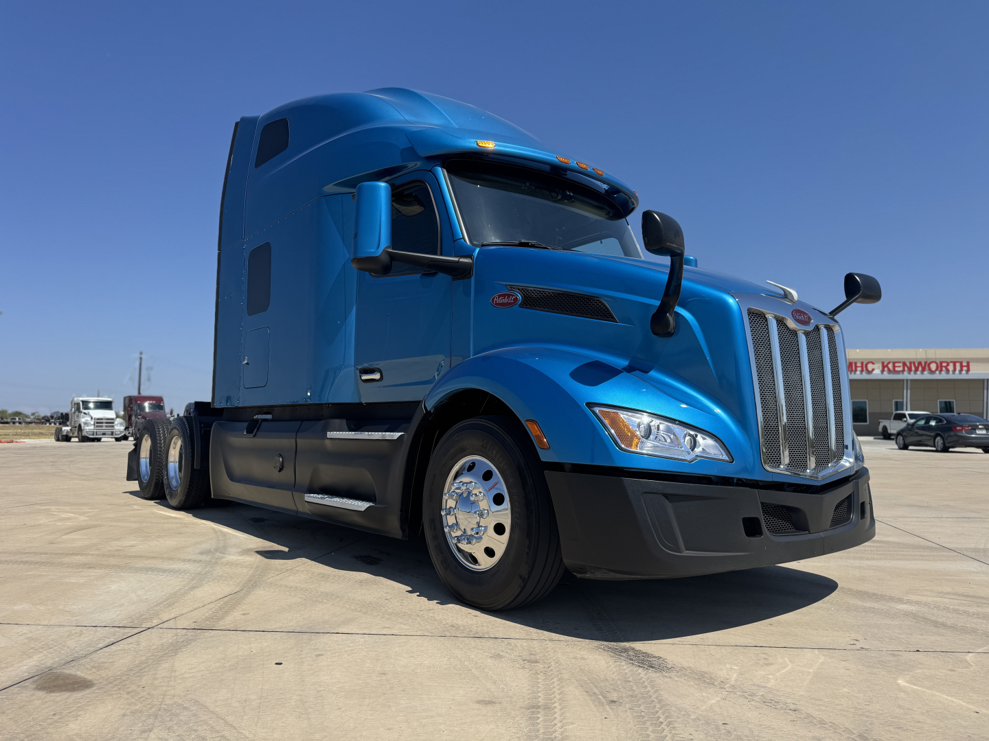Peterbilt 579 conventional sleeper truck in blue, front-left view, showing chrome grille, large side mirrors, and sleeper cab.