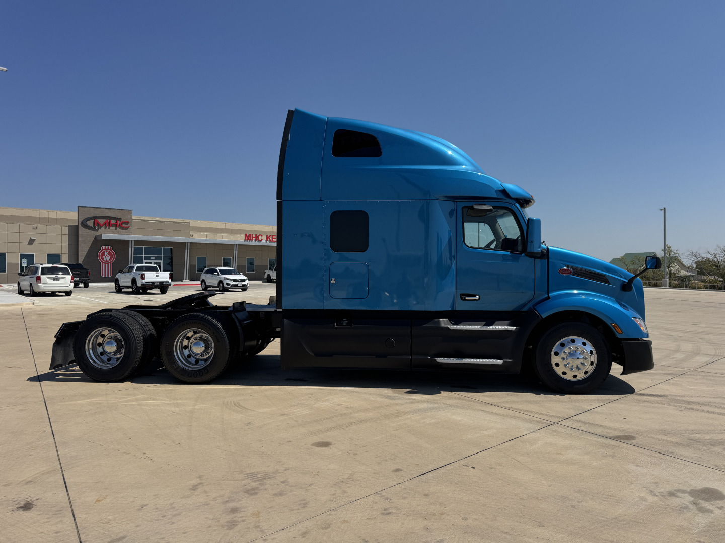 Peterbilt 579 truck side view showing blue sleepered cab and rear axles