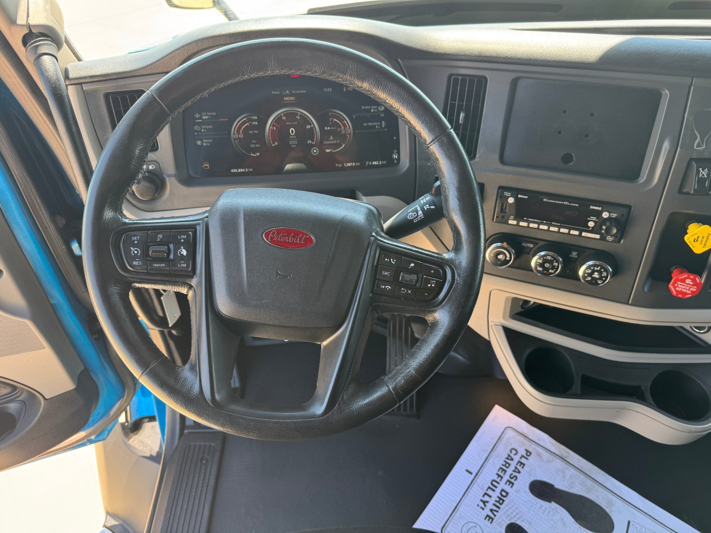Peterbilt 579 cab interior showing steering wheel, dashboard gauges, and center console with controls.