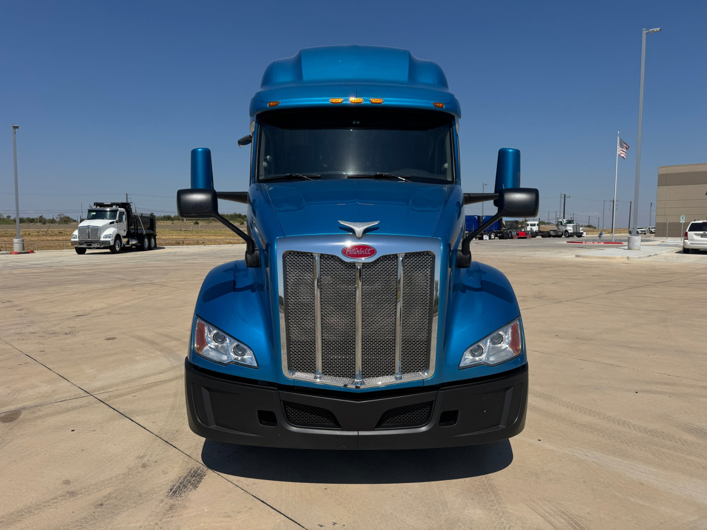 Peterbilt 579 truck front view showing chrome grille and blue cab in a parking lot.
