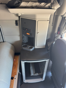 Peterbilt 579 cab interior showing dashboard with radio, controls, cup holders, and storage area.
