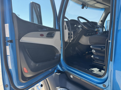 Peterbilt 579 cab interior and driver door open, steering wheel and dashboard visible.