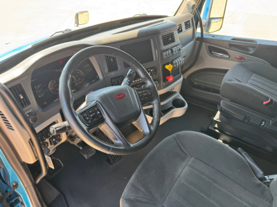 Peterbilt 579 cab interior showing steering wheel, dashboard, and driver seat with controls and switches.