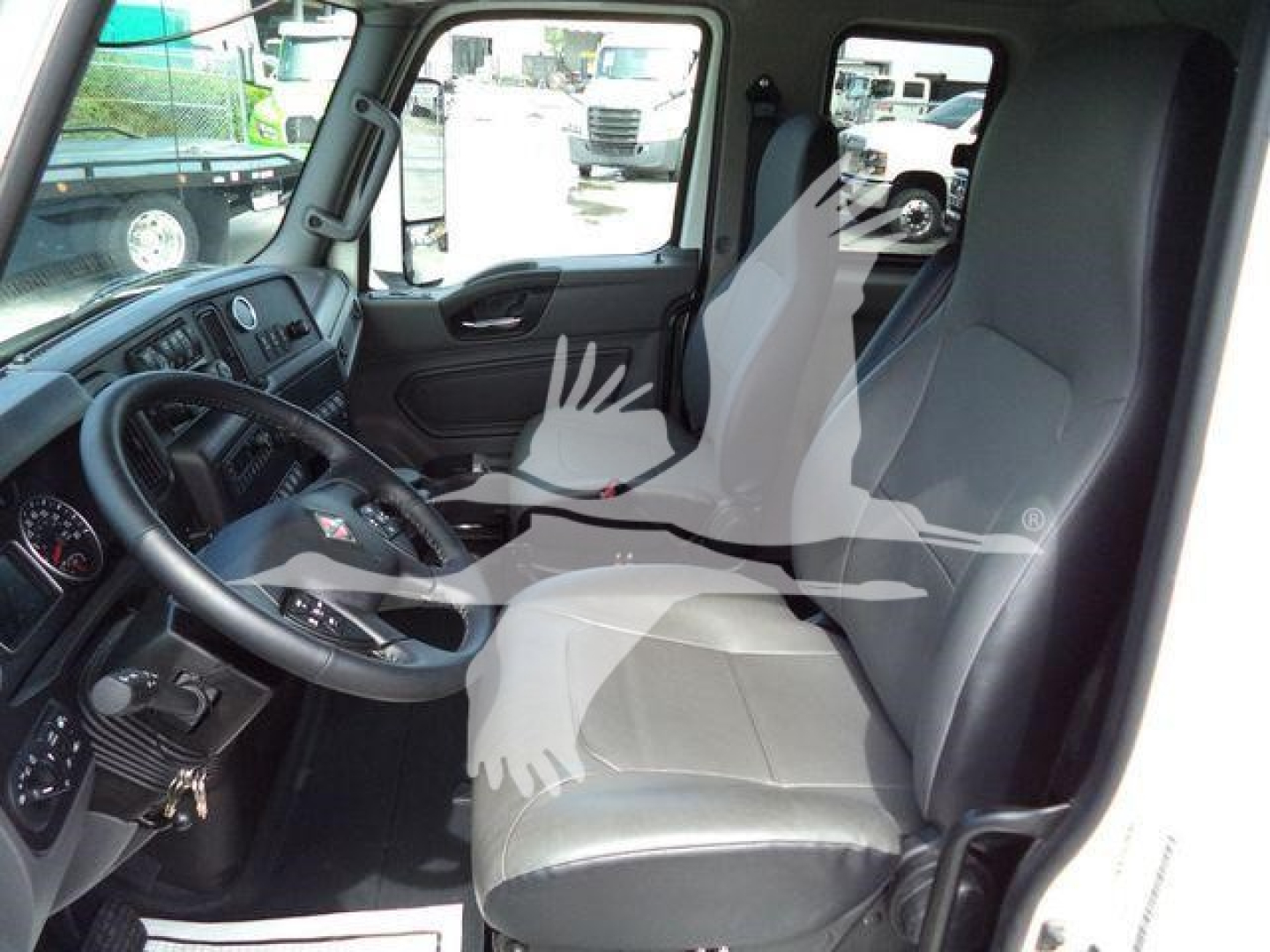 Truck cab interior view showing steering wheel, driver seat, and dashboard in a 2025 International MV from the left side.
