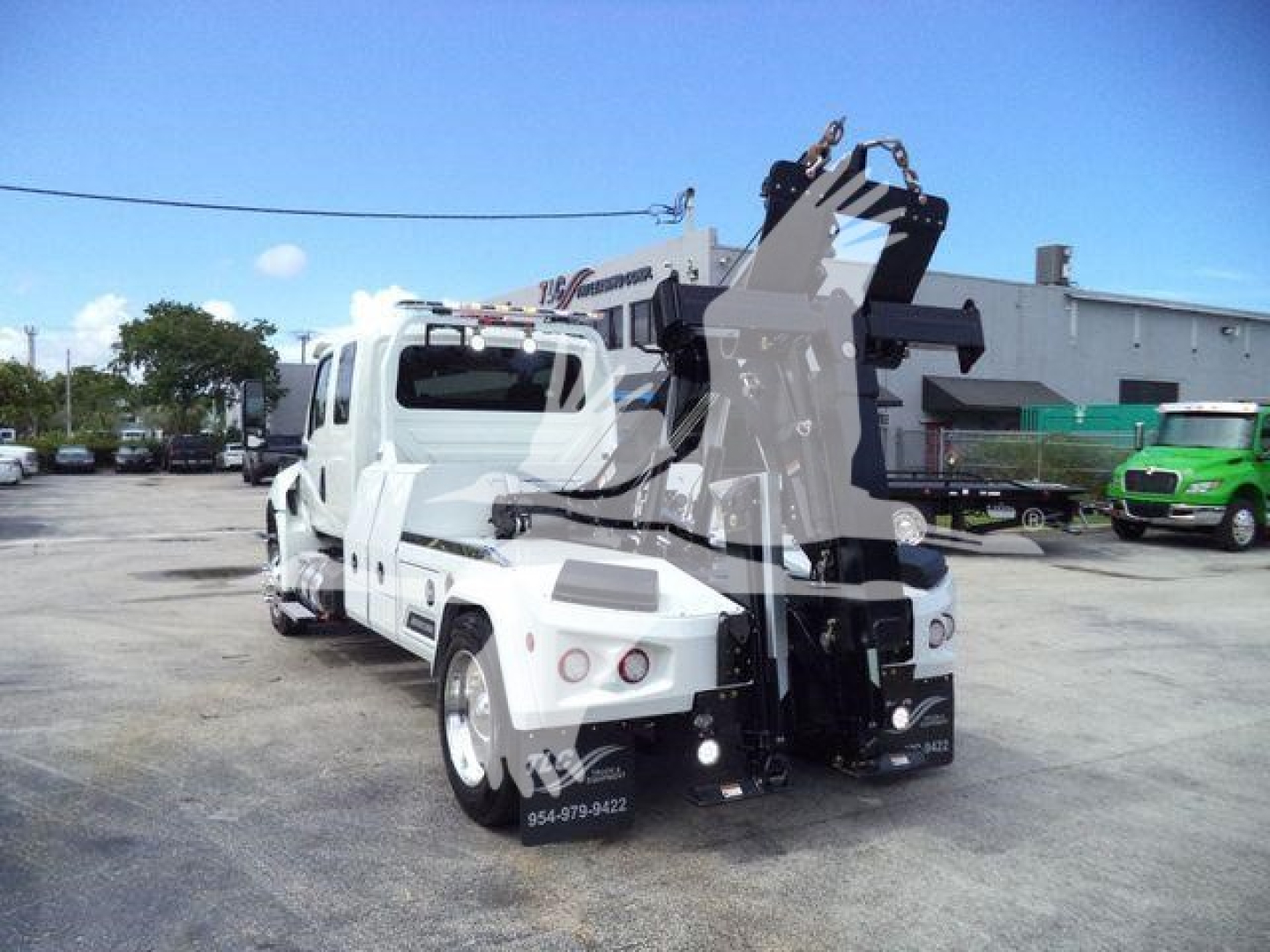 Truck featuring winch equipment mount and hitch on rear with white cab and black lifting mechanism visible.