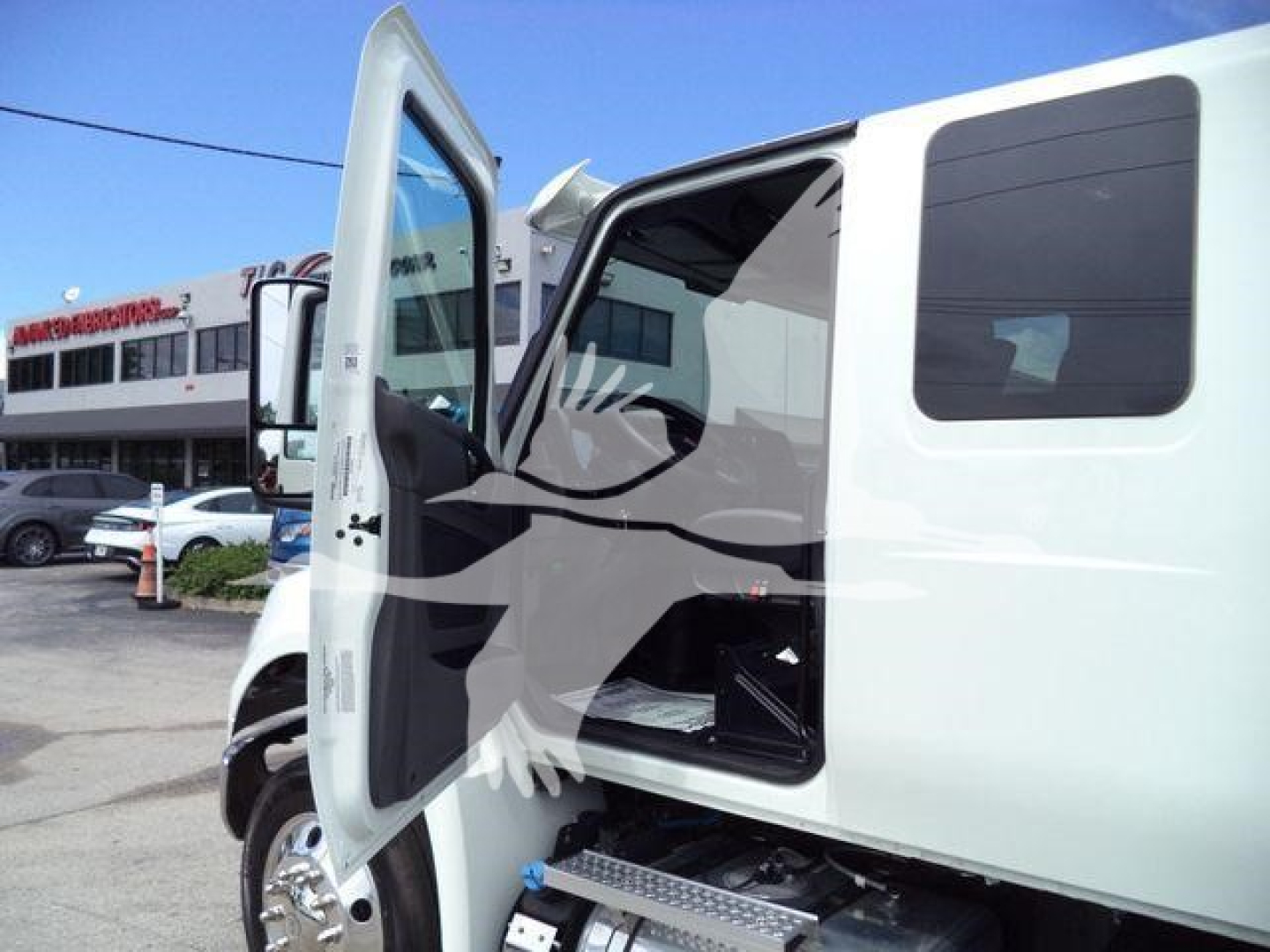 Truck cabin with open driver door showing interior steps and windowed side cab, white exterior, winch category listing on dealership lot.