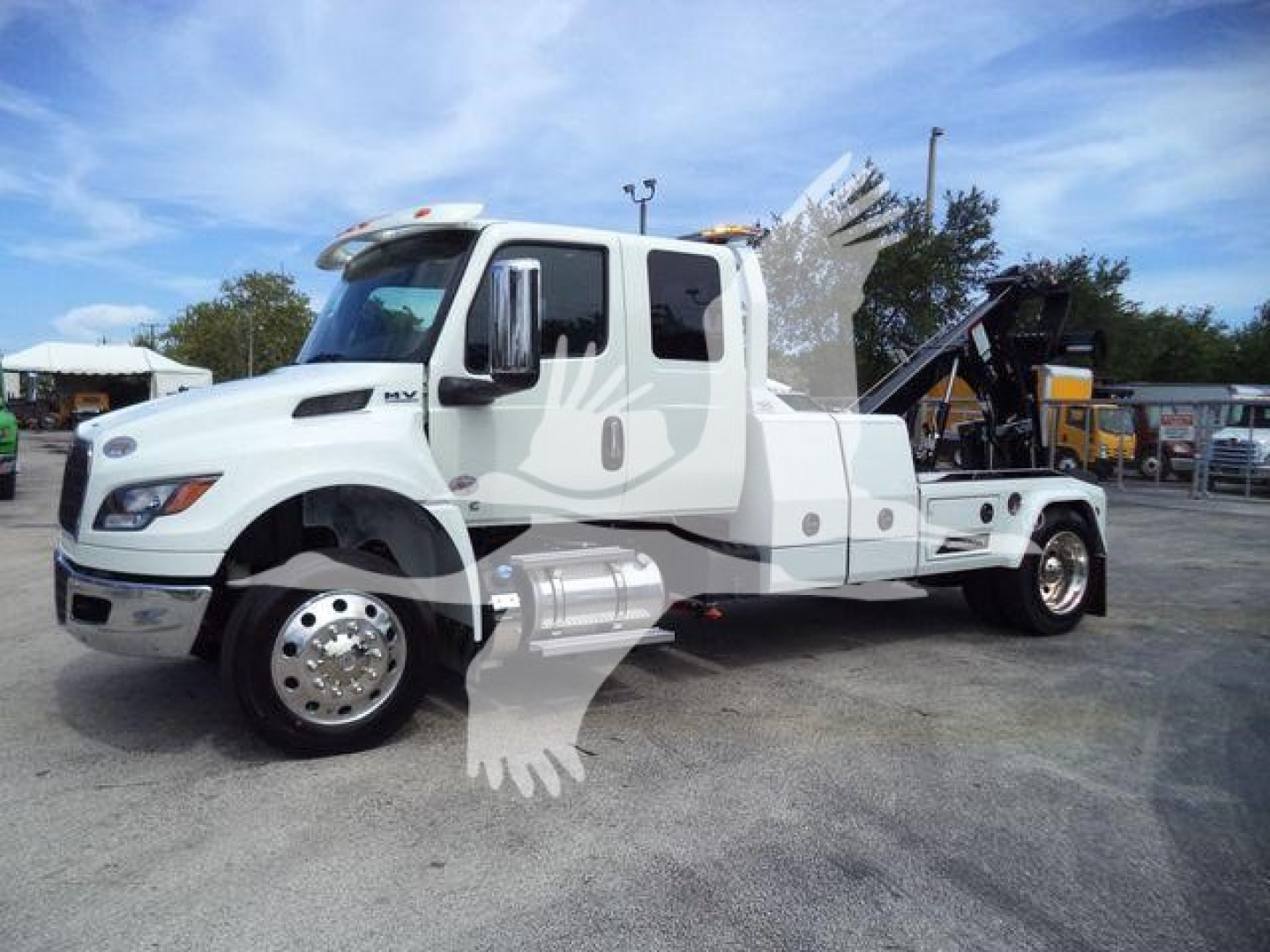 International MV truck with winch equipment on a white cab chassis, side profile view showing dual rear axles and winch/inclined bed.